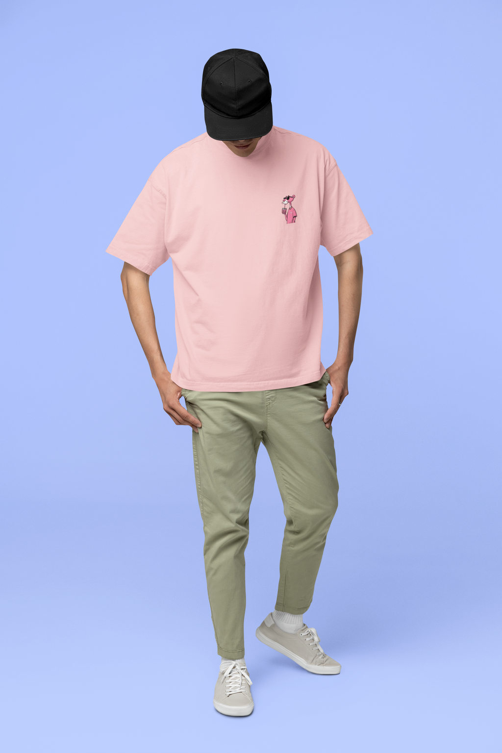 Full-body_view_of_a_man_standing_against_a_light_blue_background_looking_down_with_his_head_tilted_forward._He_is_wearing_a_light_pink_oversized_t-shirt_with_a_small_graphic_of_the_Pink panther