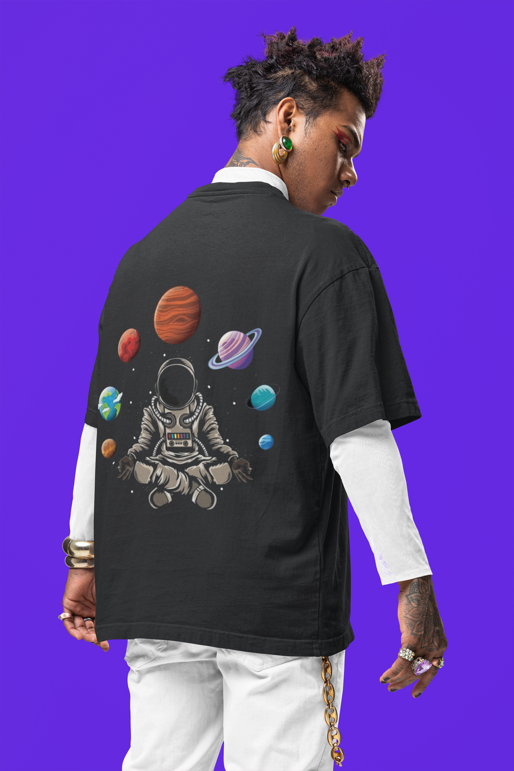 Person wearing a black t-shirt with an astronaut and space-themed design on the back against a purple background