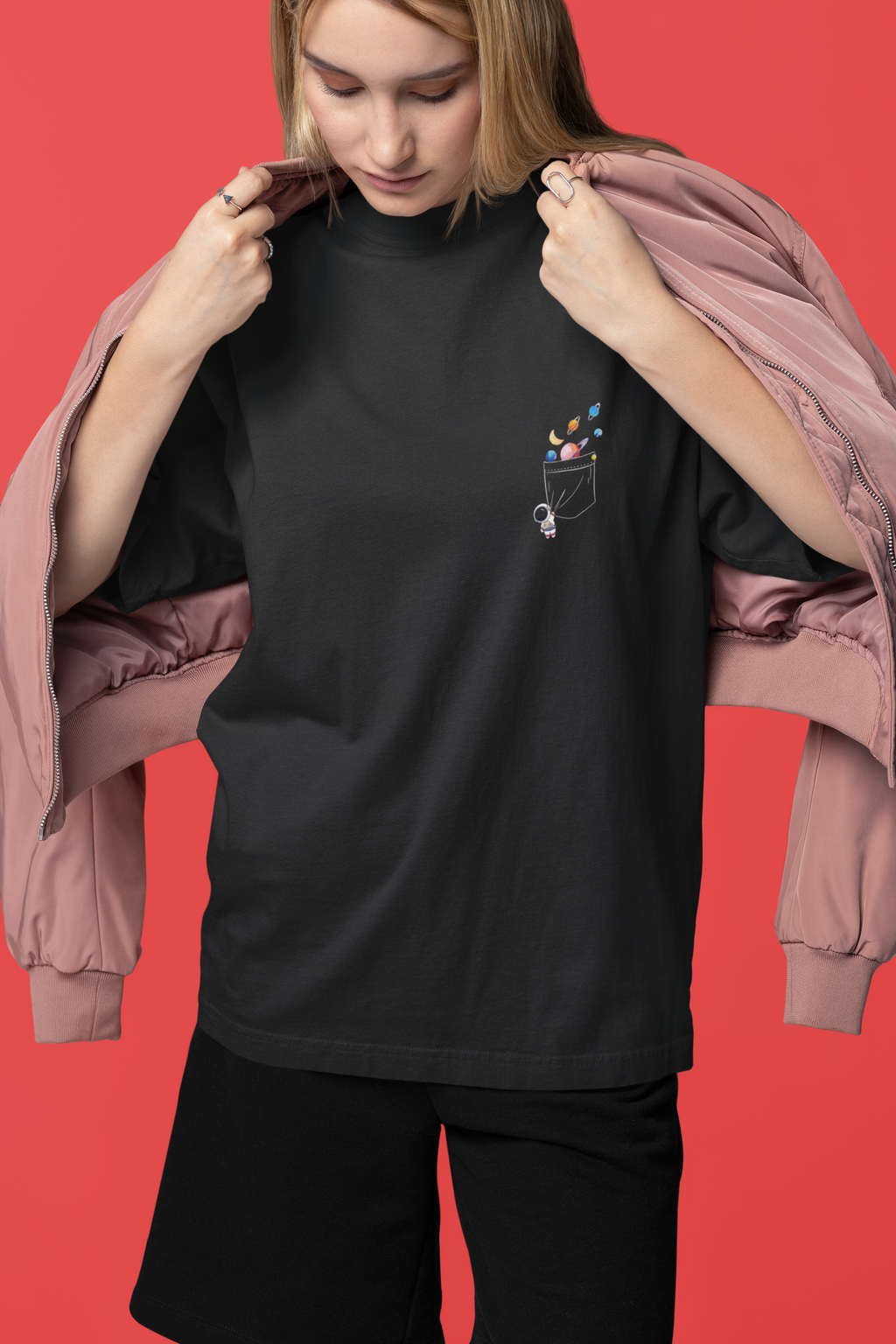 Person wearing a black t-shirt with a pocket design against a red background