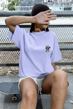 Person wearing a light purple t-shirt with a panda design, sitting on a skateboard.